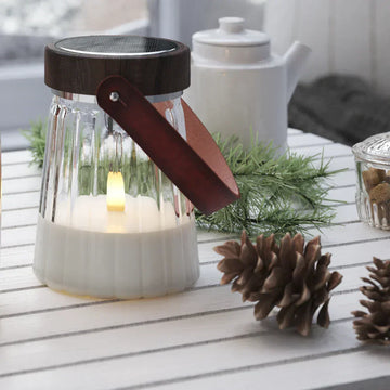 Nordic Flame LED-kaars in glazen lantaarn op witte tafel met dennenappels en winterdecoratie