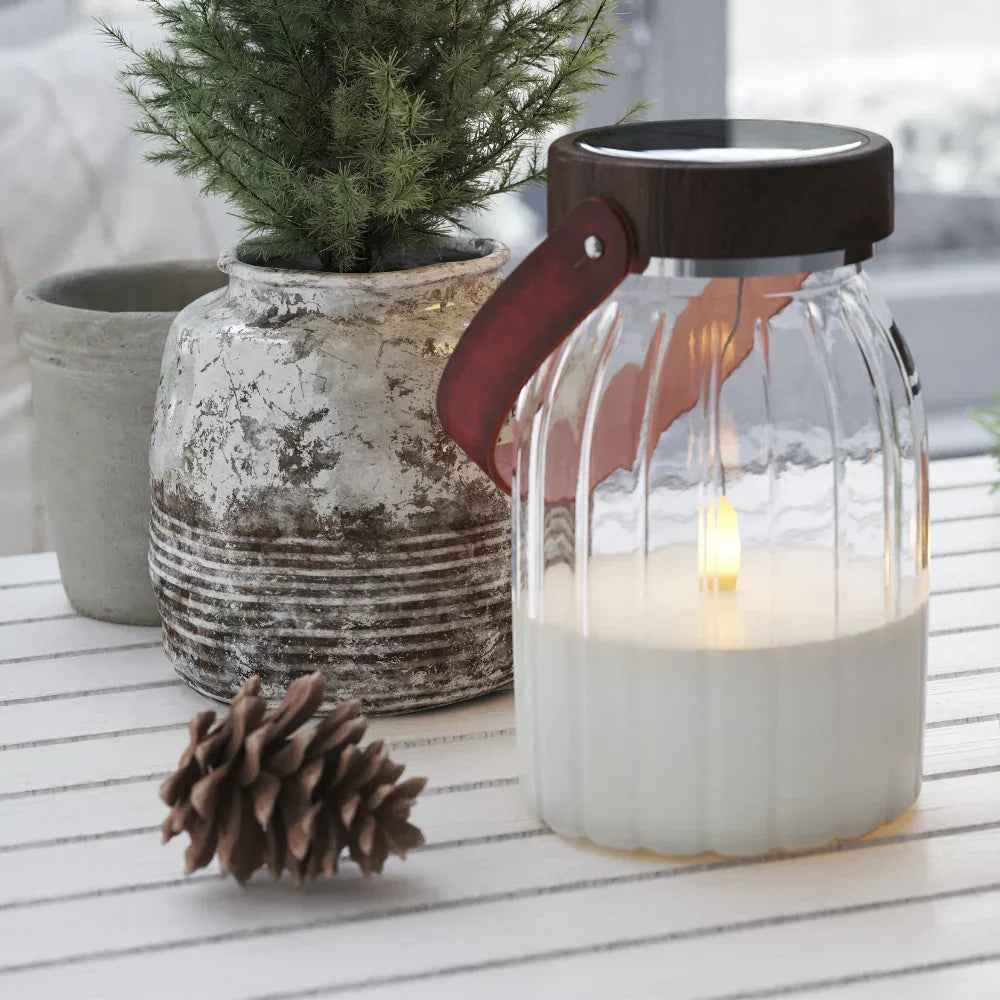 Nordic Flame LED-kaars in glazen lantaarn op een witte tafel met plant en dennenappel