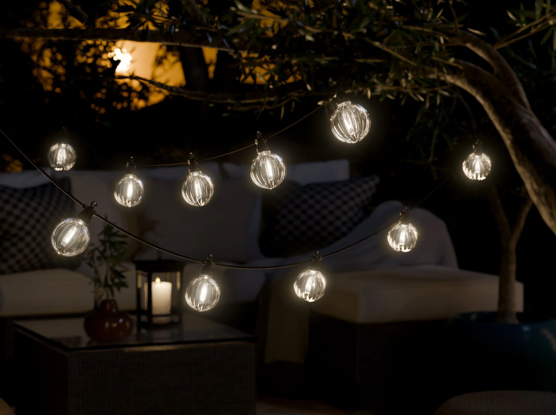 Sfeervolle buitenruimte met LED-lichtslinger en realistische LED-kaars op tafeltje