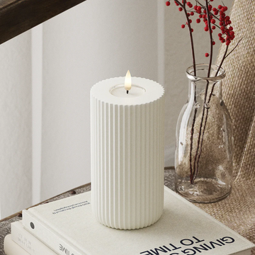 Witte LED-stompkaars van Nordic Flame met 3D-vlam op tafel, naast vaas met rode bessen.