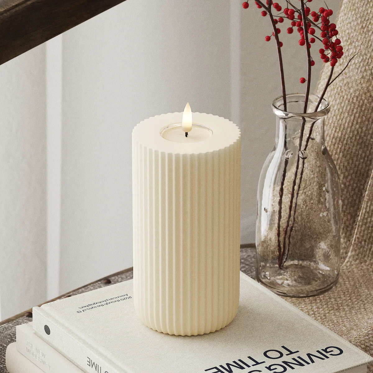 Realistische LED-stompkaars van Nordic Flame, ivoorwit, op boek in gezellige interieursetting