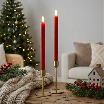 Twee rode LED-dinerkaarsen van Nordic Flame op tafel, sfeervol met kerstdecoratie en kerstboom.