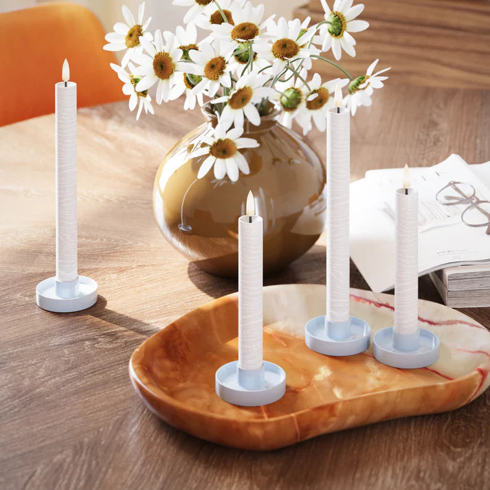Set van vier realistische LED-dinerkaarsen in witte houders op houten tafel met vaas bloemen