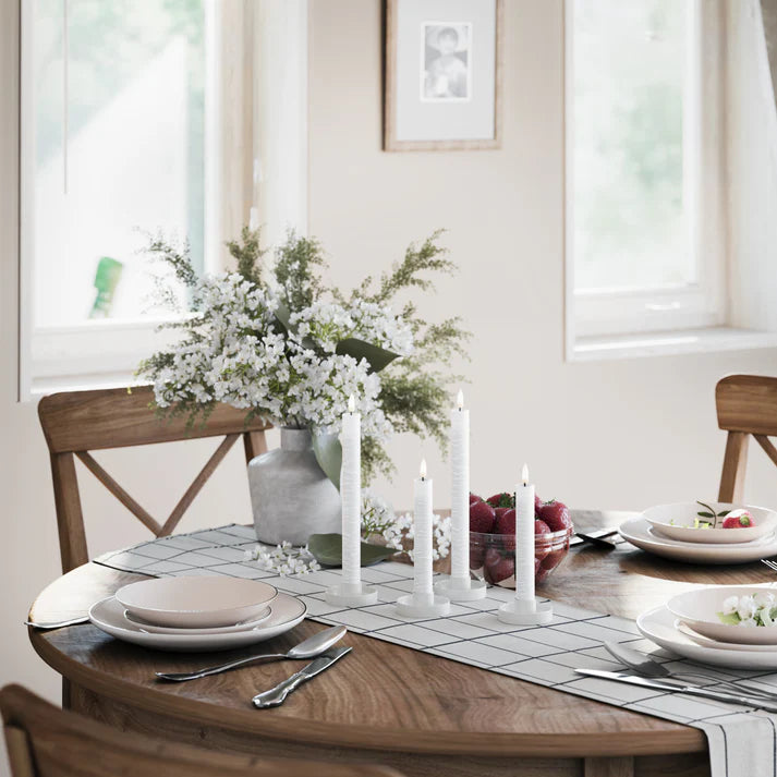 LED dinerkaarsen van Nordic Flame op houten eettafel met bloemen en servies in natuurlijk daglicht