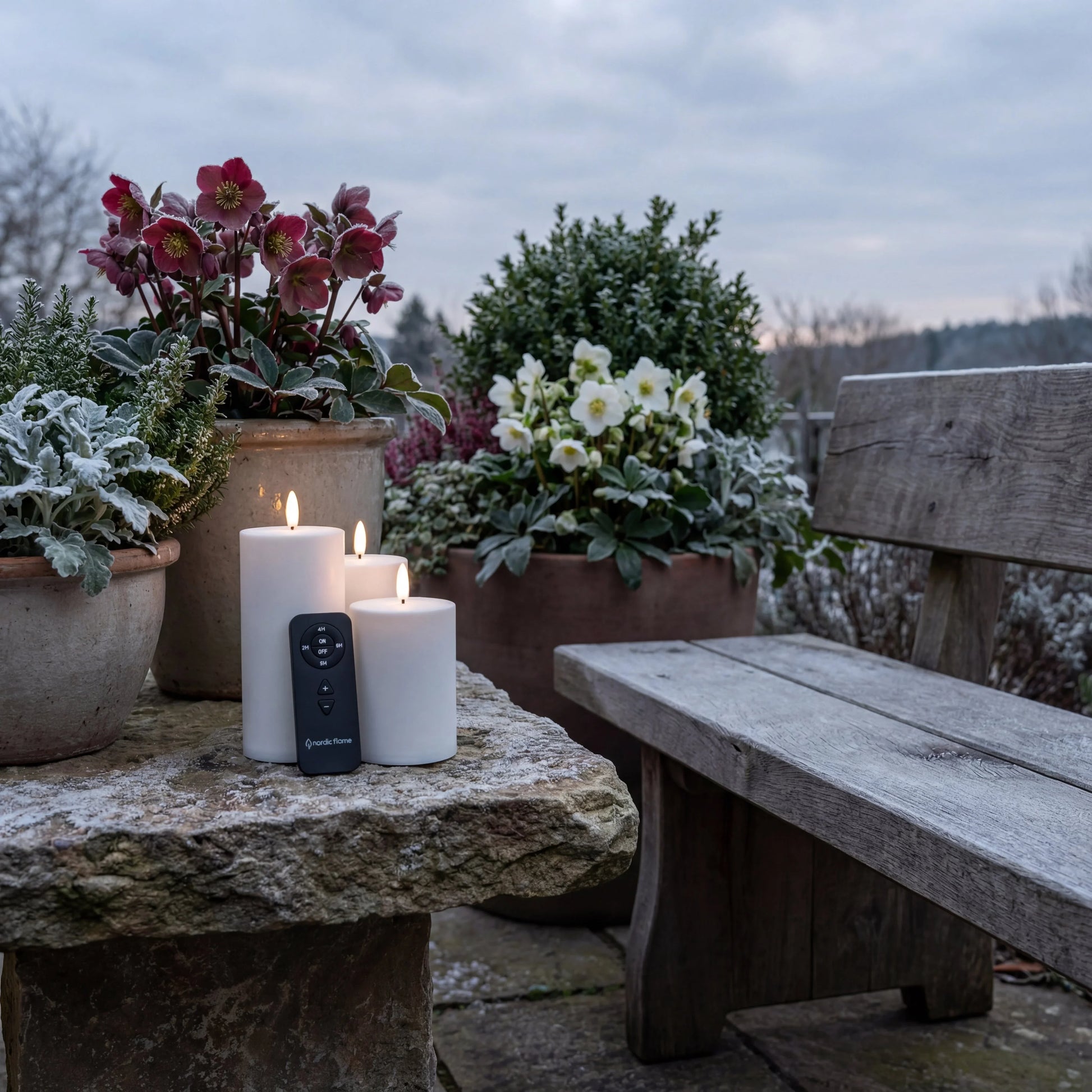 Set van drie witte Nordic Flame LED-kaarsen met afstandsbediening op tuintafel buiten