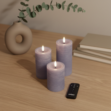 Set van drie paarse LED-stompkaarsen met 3D-vlam en afstandsbediening op houten tafel